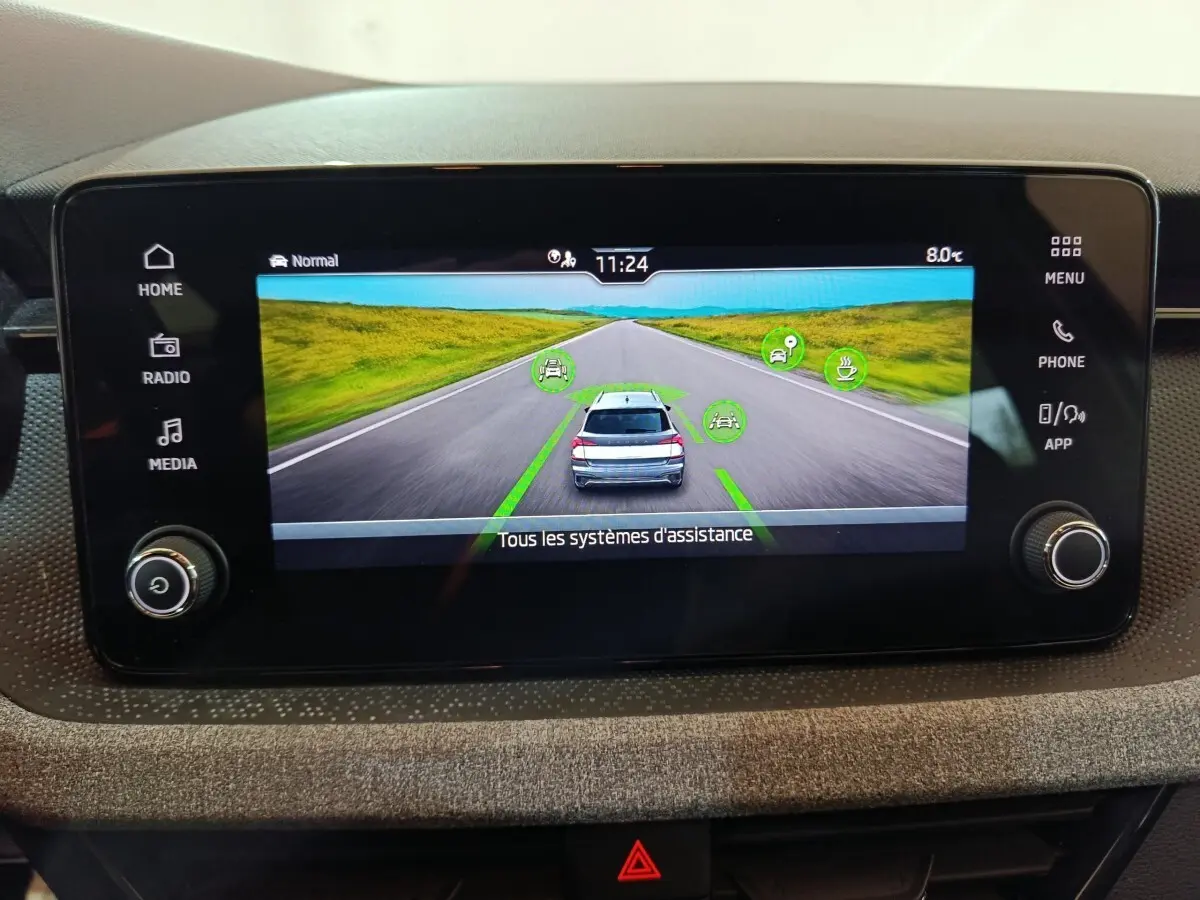Écran tactile central affichant l’aide à la conduite avec vue arrière d’un Skoda Kamiq gris clair sur route droite.