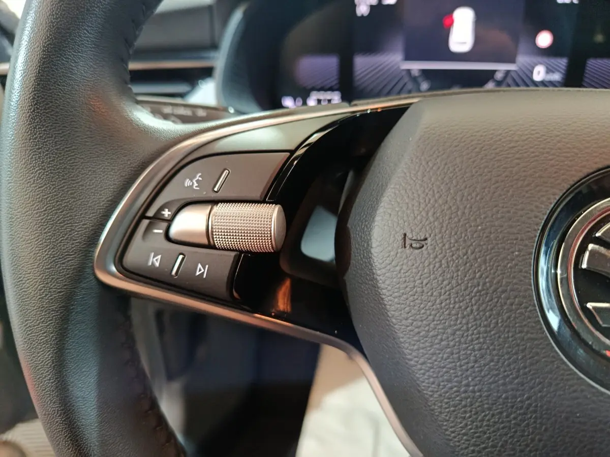 Gros plan sur le volant cuir noir du Skoda Kamiq 2024, avec commandes audio et molette métallique côté gauche.