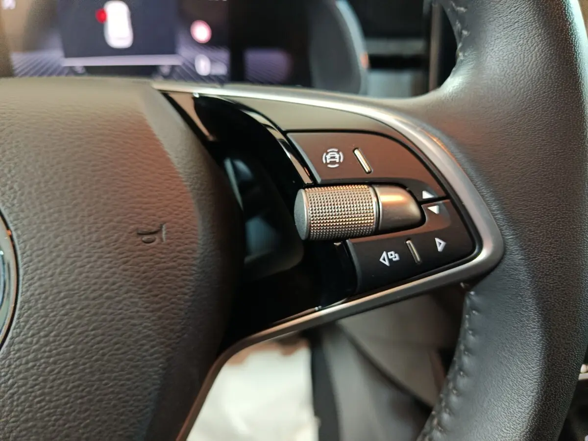 Gros plan sur les commandes droite du volant cuir noir du Skoda Kamiq gris clair 2024, avec molette et boutons multifonctions.