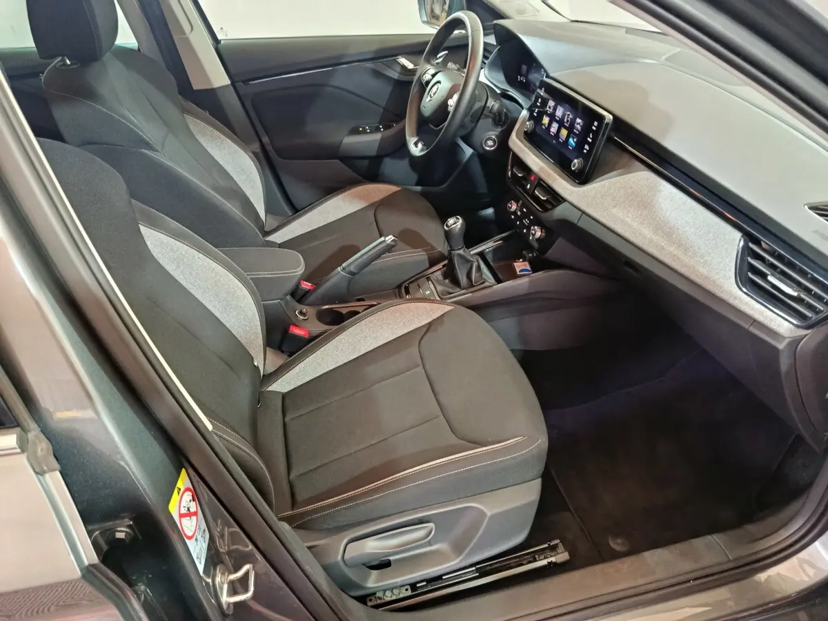 Intérieur avant droit du Skoda Kamiq gris clair 2024, sièges bi-ton, tableau de bord avec écran tactile central.