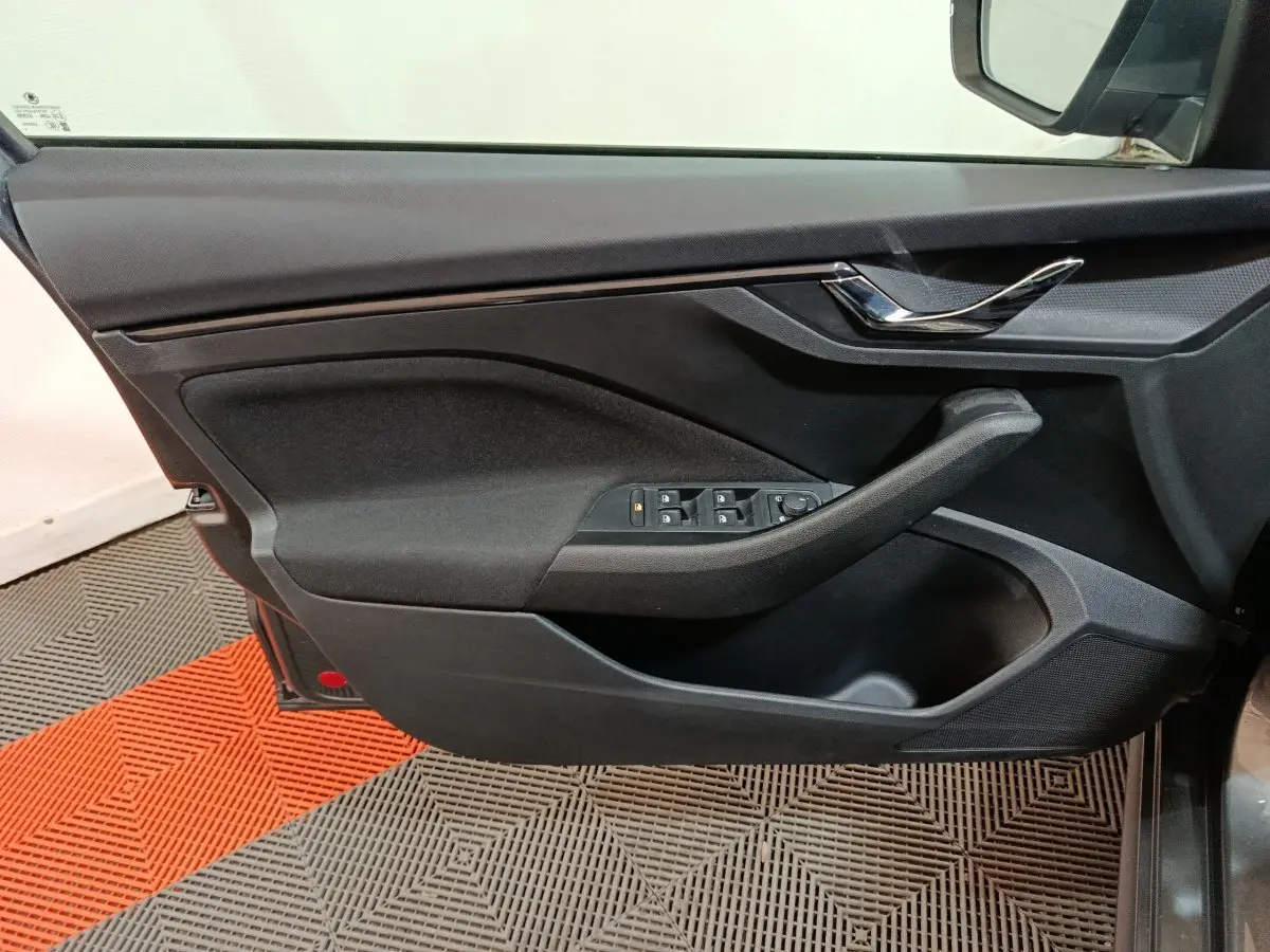 Vue rapprochée de la porte avant gauche noire du Skoda Kamiq 2024 avec commandes de vitres et poignée chromée.