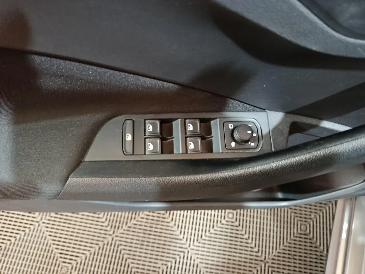 Vue rapprochée des commandes de lève-vitres et rétroviseurs sur la porte côté conducteur d'un Skoda Kamiq gris clair 2024.