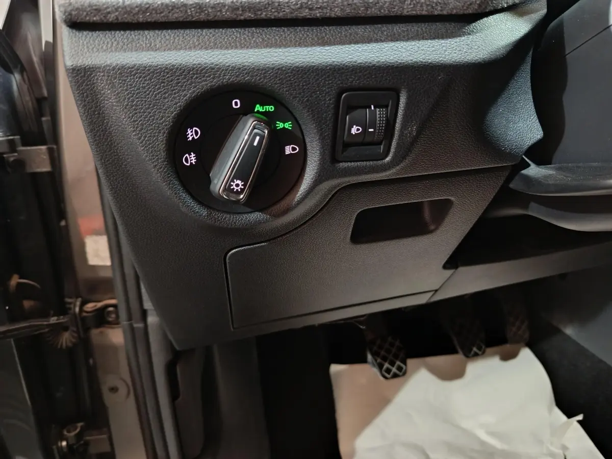 Détail du panneau de commande des phares avec réglage de hauteur, côté gauche intérieur d’un Skoda Kamiq gris clair 2024.