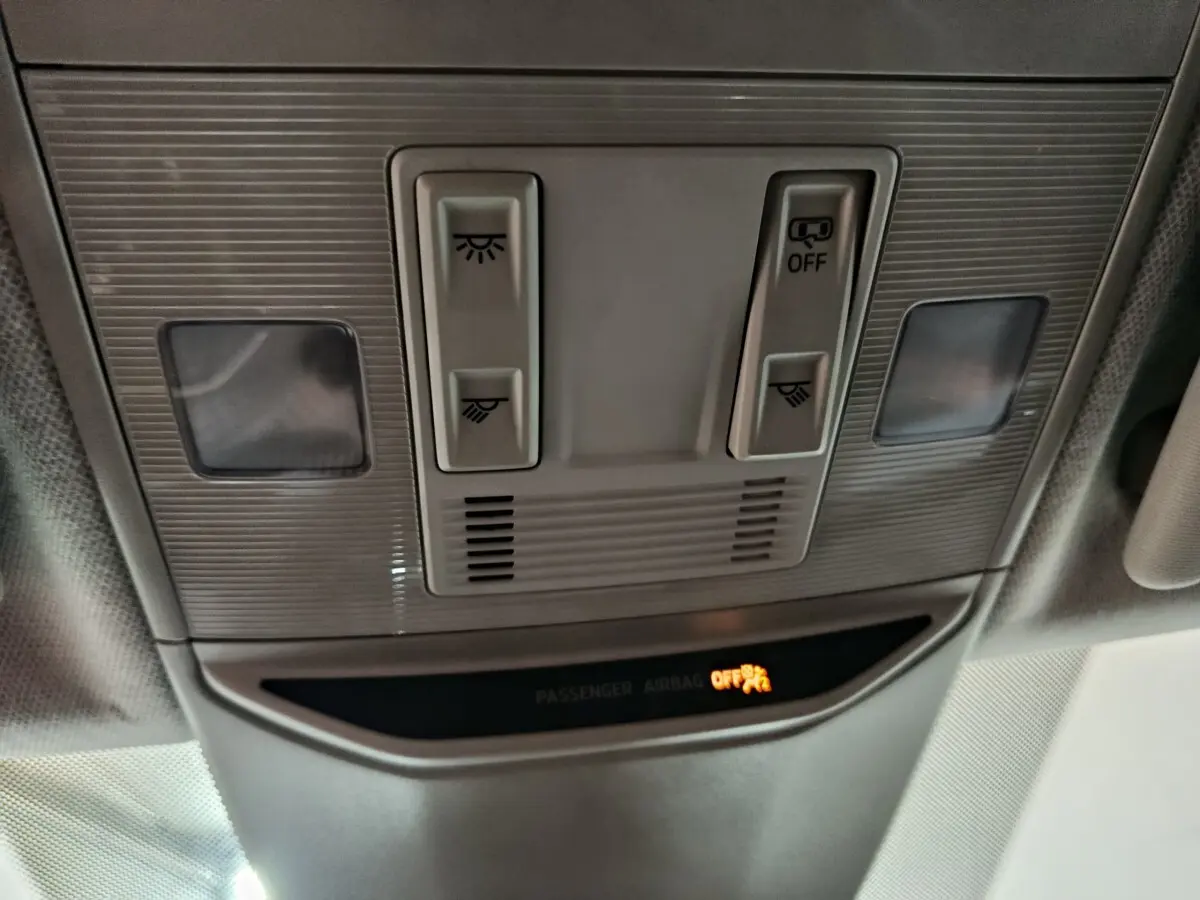 Vue en plongée du plafonnier gris clair du Skoda Kamiq 2024 avec commandes d'éclairage et témoin airbag passager éteint.