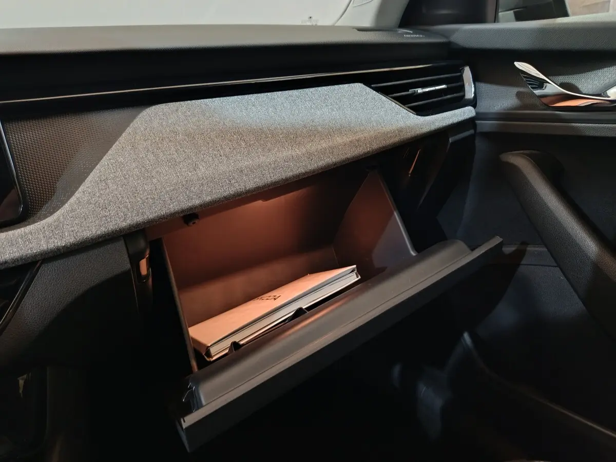 Vue intérieure côté passager du coffre à gants ouvert du Skoda Kamiq gris clair 2024 avec manuel visible.