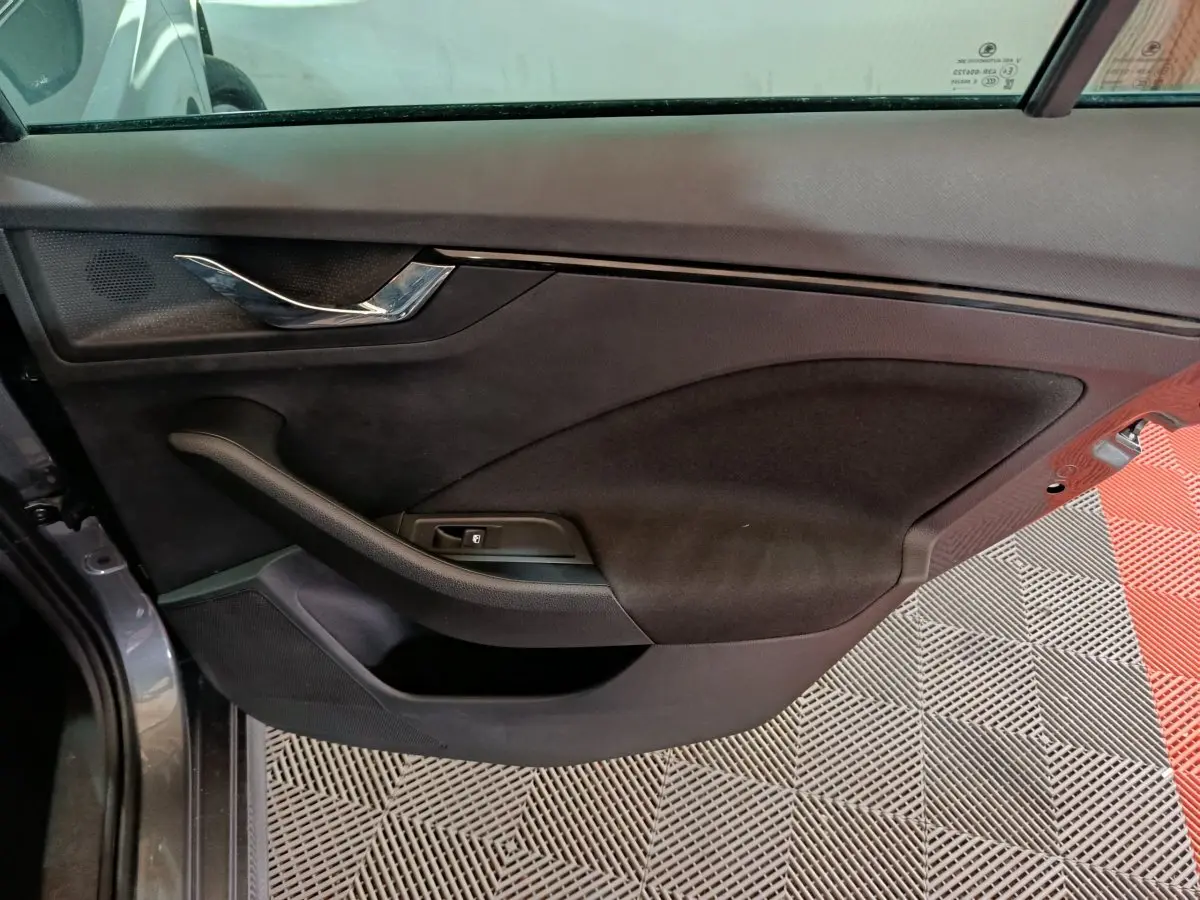 Vue rapprochée de la porte avant gauche intérieure du Skoda Kamiq gris clair, avec poignée chromée et commande de vitre.