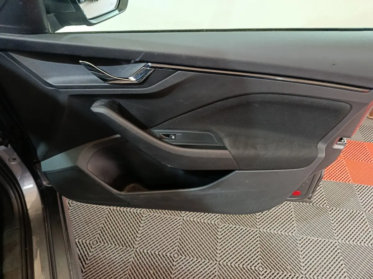 Vue intérieure côté gauche de la porte avant gris clair du Skoda Kamiq 2024 avec poignée et commande de vitre.