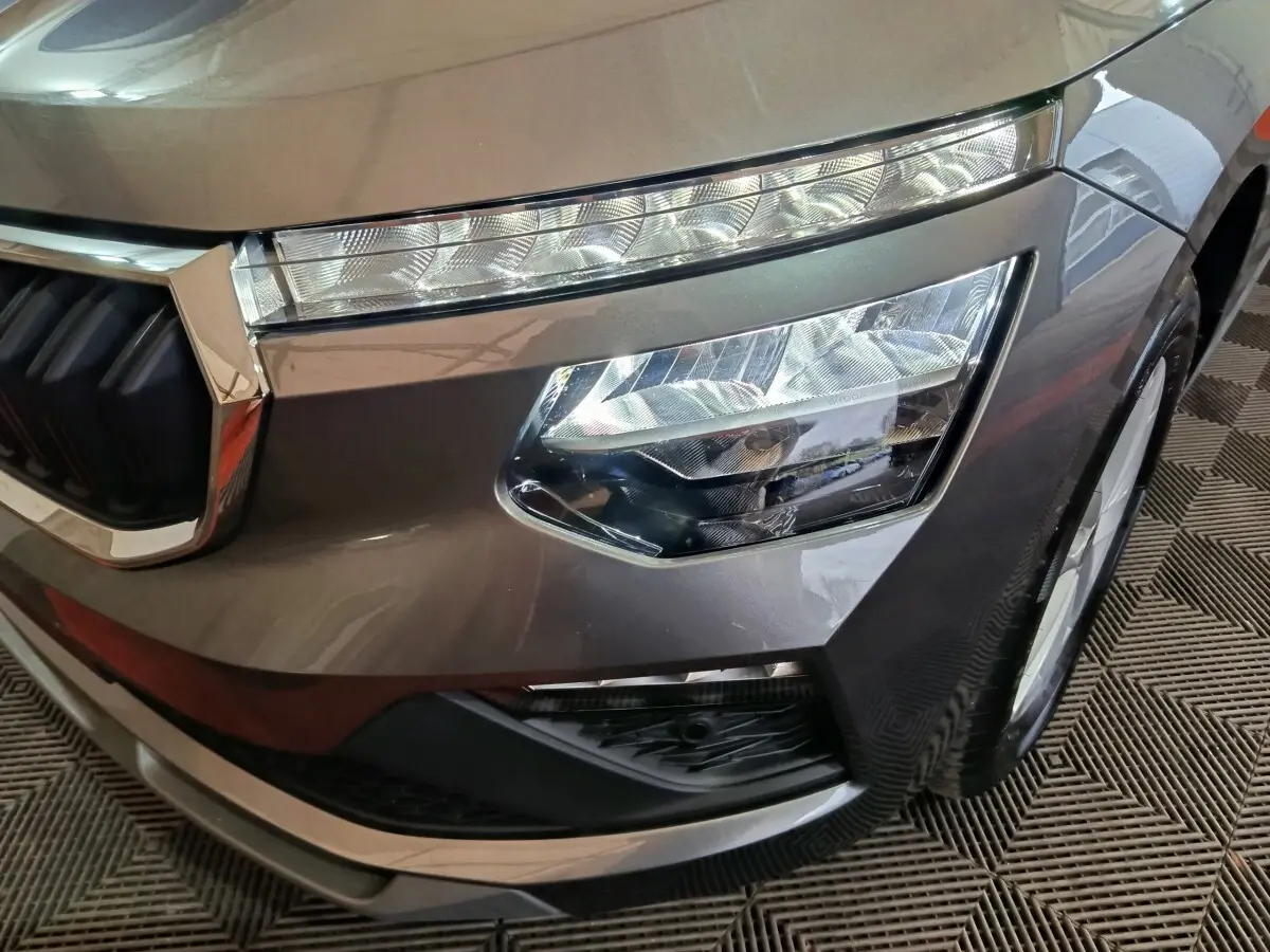 Gros plan sur le phare avant droit gris clair du Skoda Kamiq 2024 avec calandre chromée et feux LED distinctifs.
