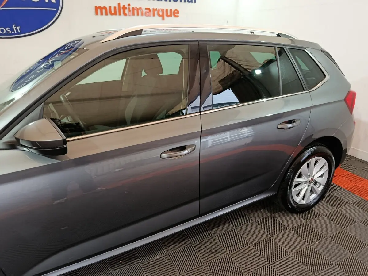 Profil côté gauche d'un Skoda Kamiq gris clair 2024 avec jantes alliage et rétroviseurs électriques chauffants.