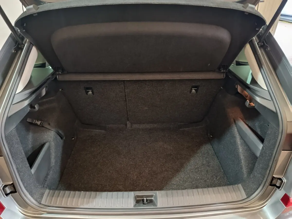 Coffre ouvert vu de l'arrière d'un Skoda Kamiq gris clair, montrant un espace de chargement vide et bien fini.