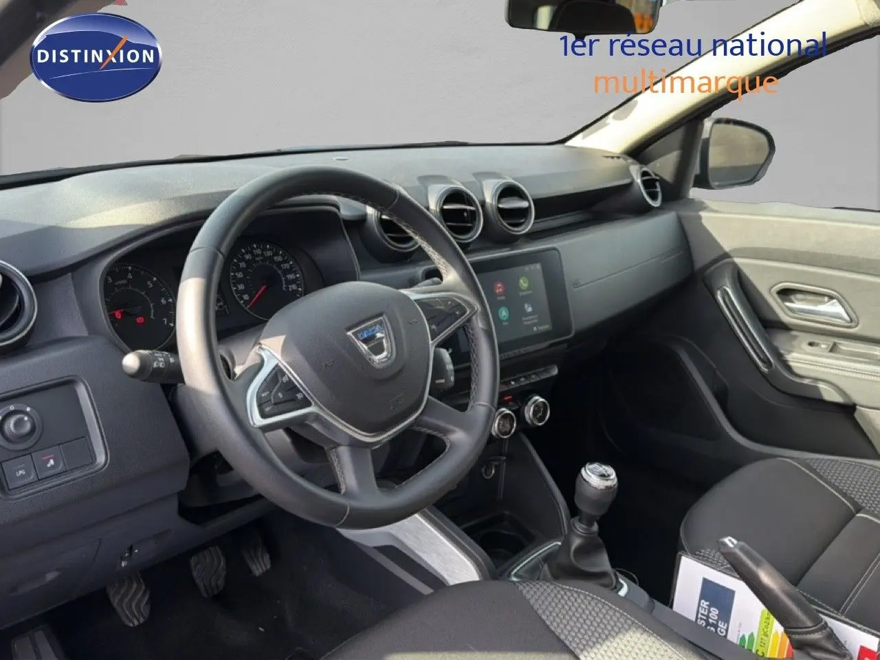 Vue intérieure côté conducteur du Dacia Duster 1.0 ECO-G 100 Prestige 2022, tableau de bord et volant noirs.