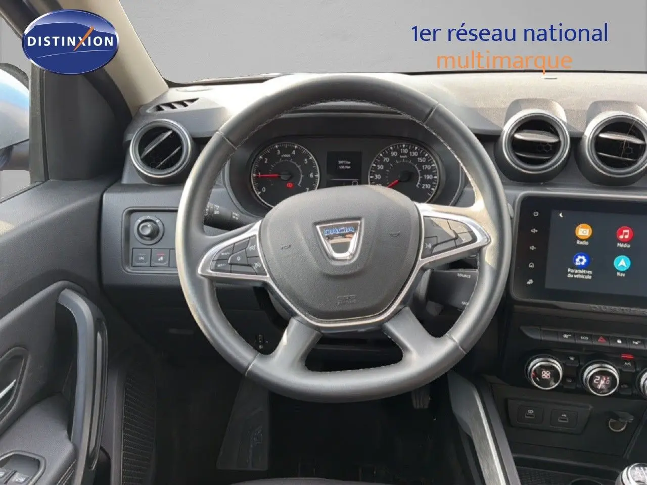 Vue intérieure centrée sur le volant du Dacia Duster 2022, tableau de bord et écran tactile visibles.