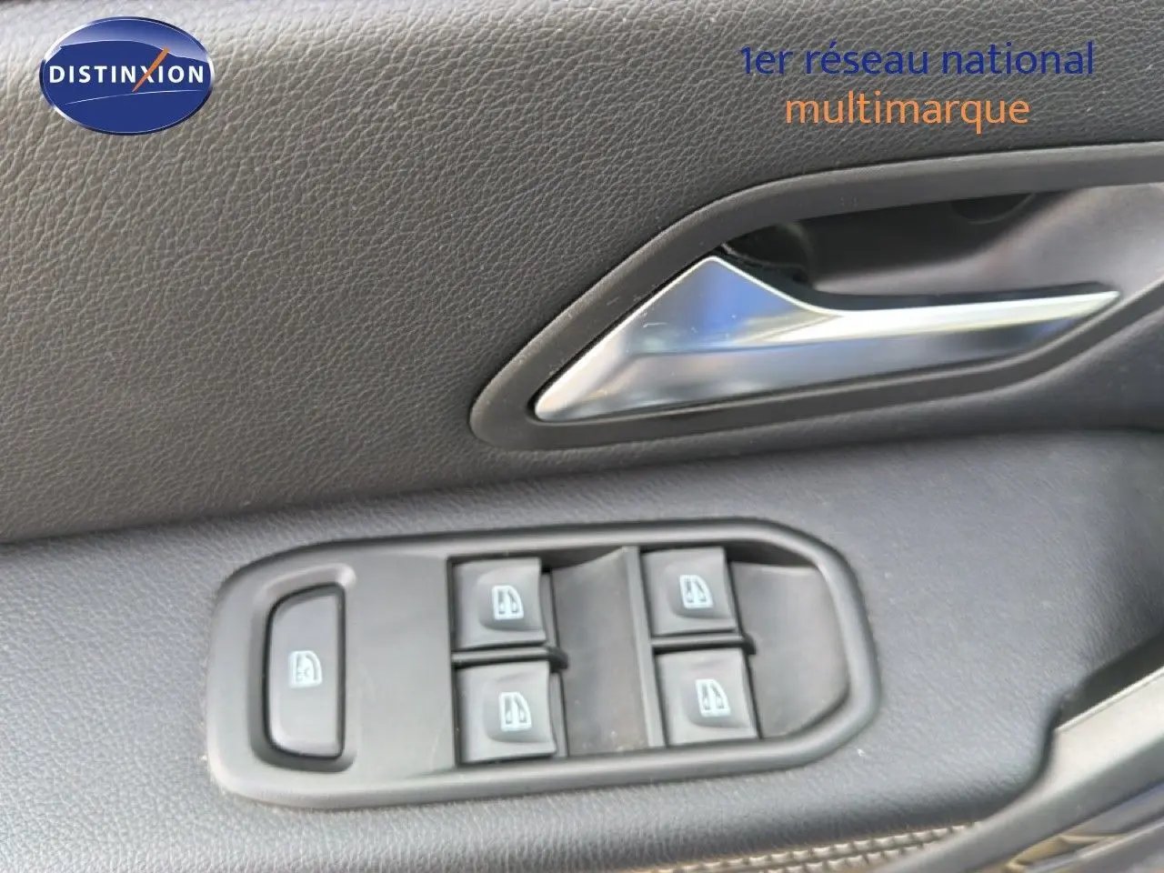 Détail des commandes des vitres et poignée de porte intérieure en plastique noir du Dacia Duster 2022.