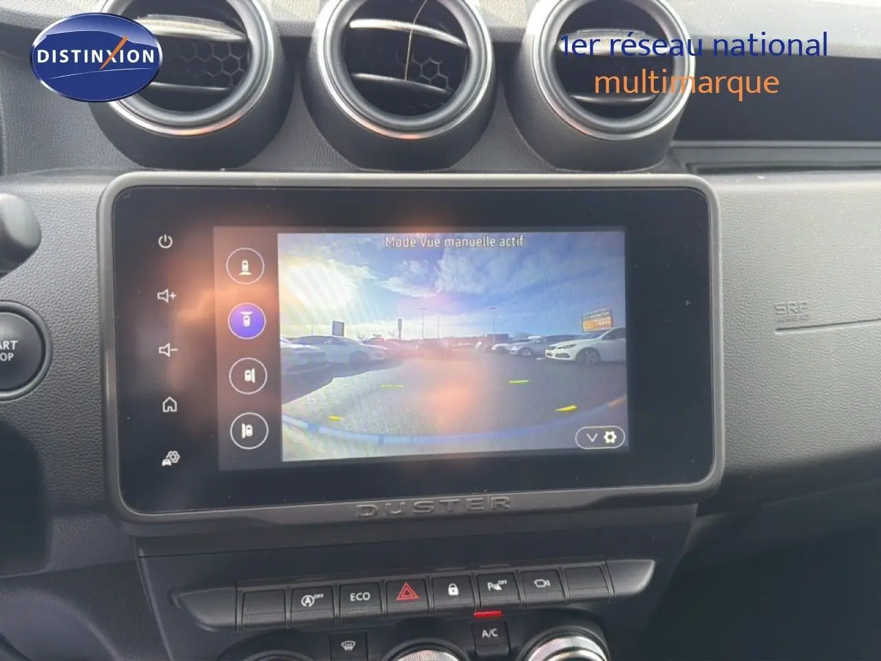 Vue intérieure centrée sur l'écran tactile du tableau de bord du Dacia Duster 2022, avec commandes et aérateurs visibles.