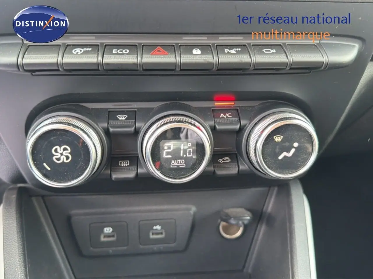 Gros plan sur la console centrale du Dacia Duster bleu Iron 2022, montrant les commandes de climatisation et les ports USB.