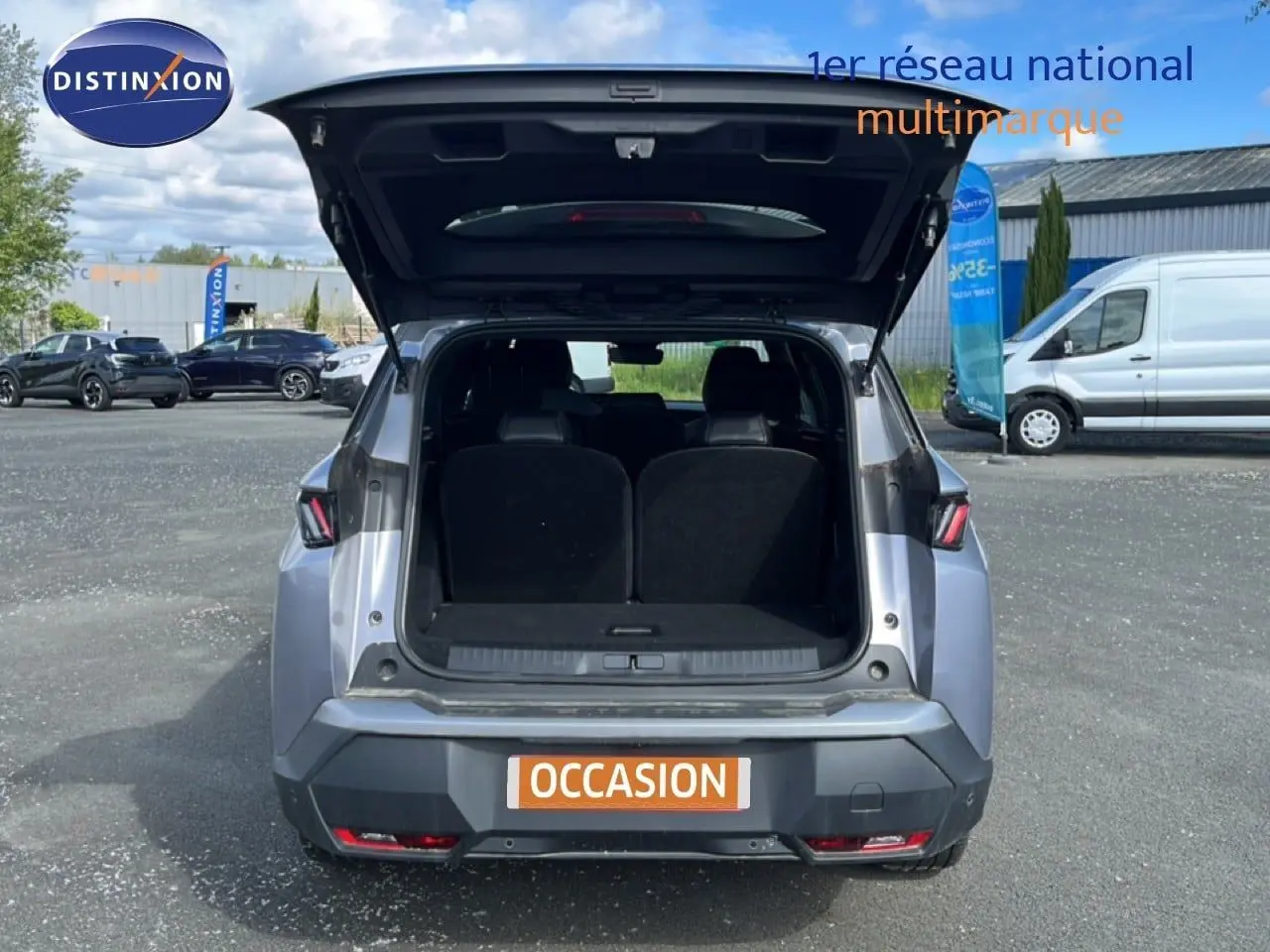 Vue arrière du Peugeot 5008 gris Artense métal 2025 avec coffre ouvert, montrant l'espace intérieur du SUV hybride.