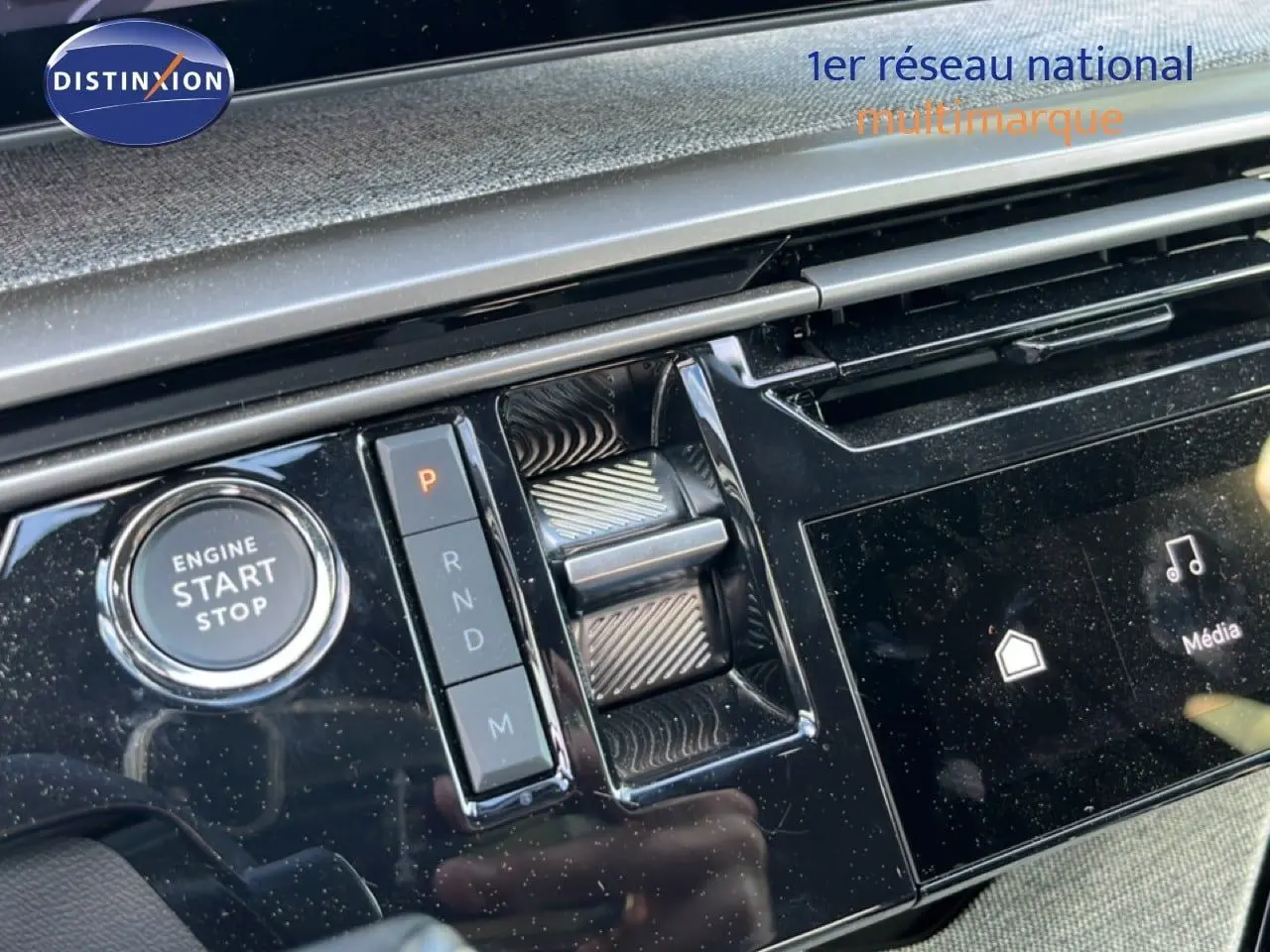 Gros plan sur la console centrale noire brillante du Peugeot 5008 gris, avec bouton start/stop et sélecteur de vitesses.