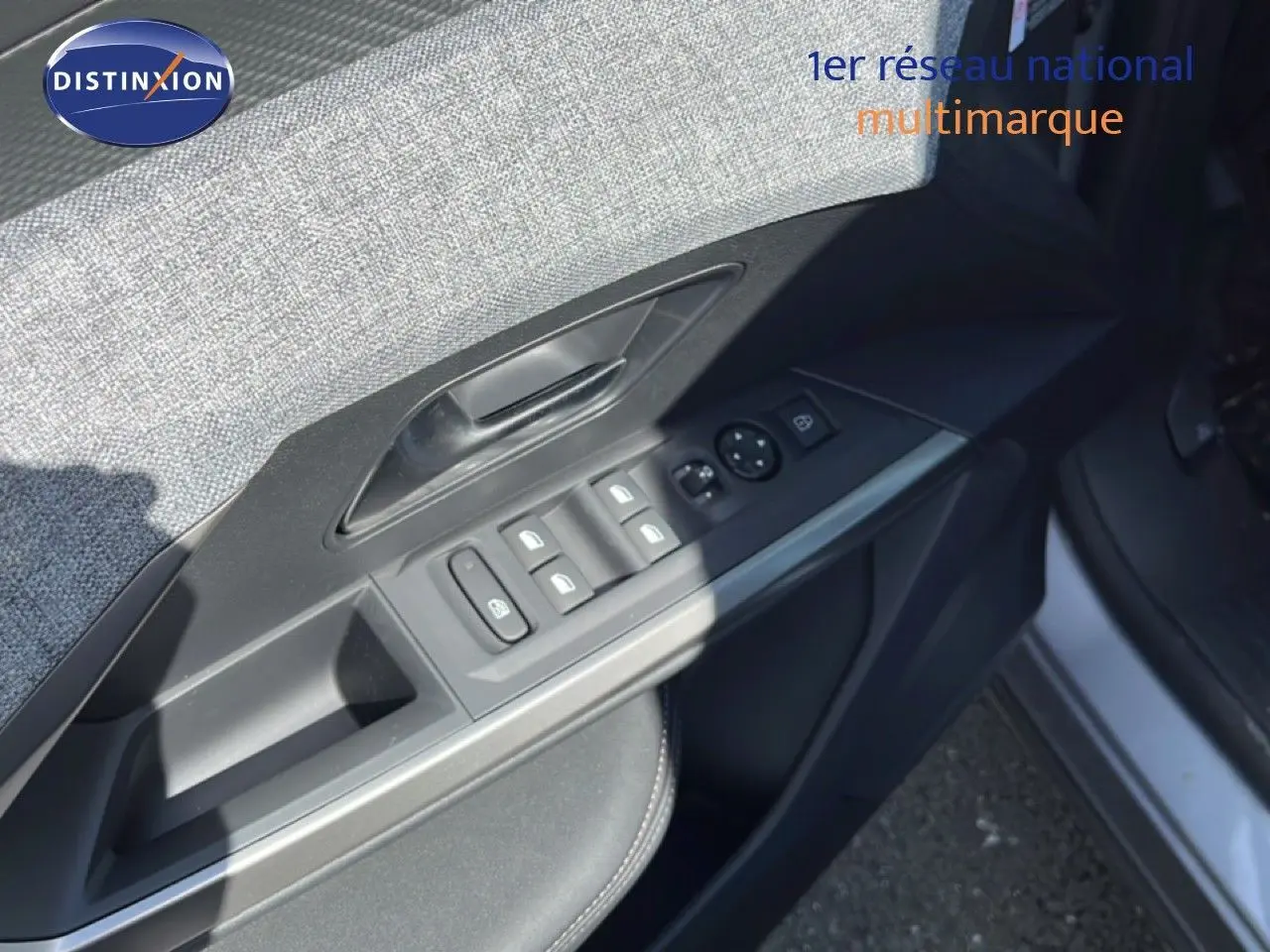 Gros plan sur la commande des vitres côté gauche d'une Peugeot 5008 gris Artense métal, intérieur tissu et cuir noir.