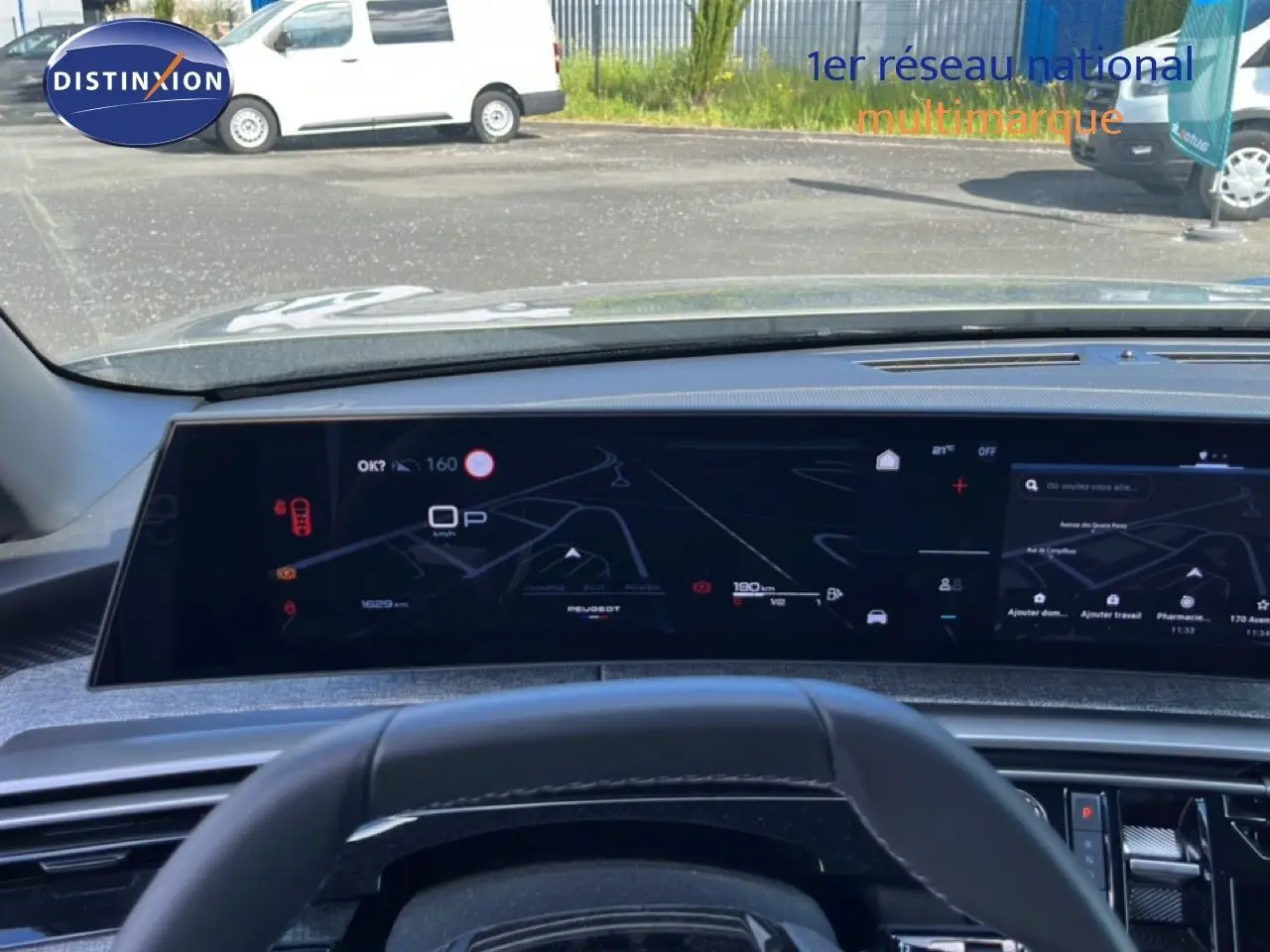 Vue intérieure du tableau de bord numérique du Peugeot 5008 gris, avec affichage de navigation et informations de conduite.