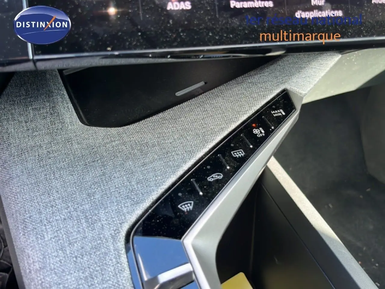 Détail de la console centrale inclinée avec commandes tactiles et finition tissu gris clair dans un Peugeot 5008 2025.