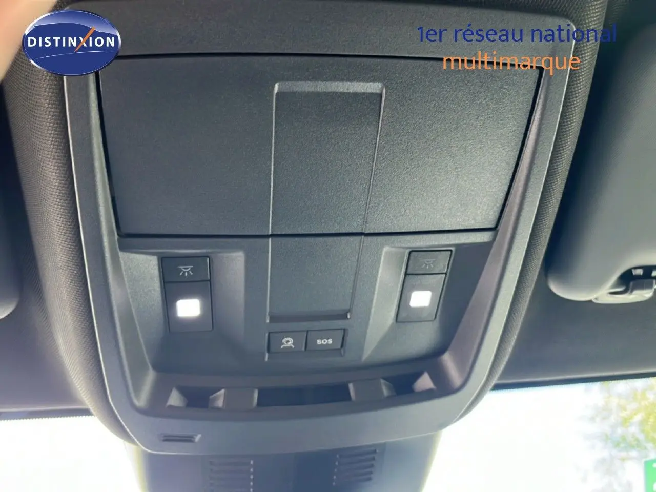 Vue en contre-plongée du plafonnier intérieur noir du Peugeot 5008 gris Artense, avec boutons d’éclairage et SOS visibles.