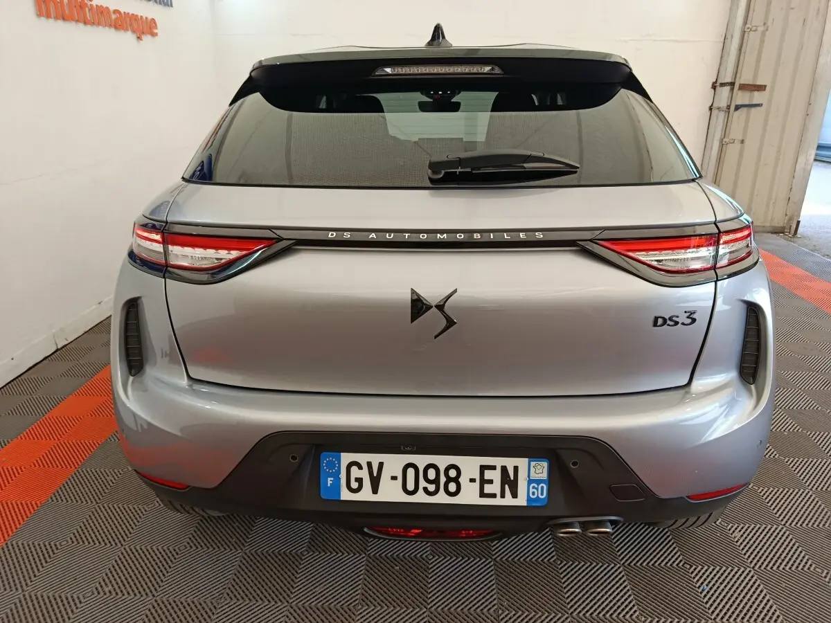Vue arrière d'une DS3 gris foncé 2024 avec feux LED et double sortie d'échappement visible en intérieur showroom.