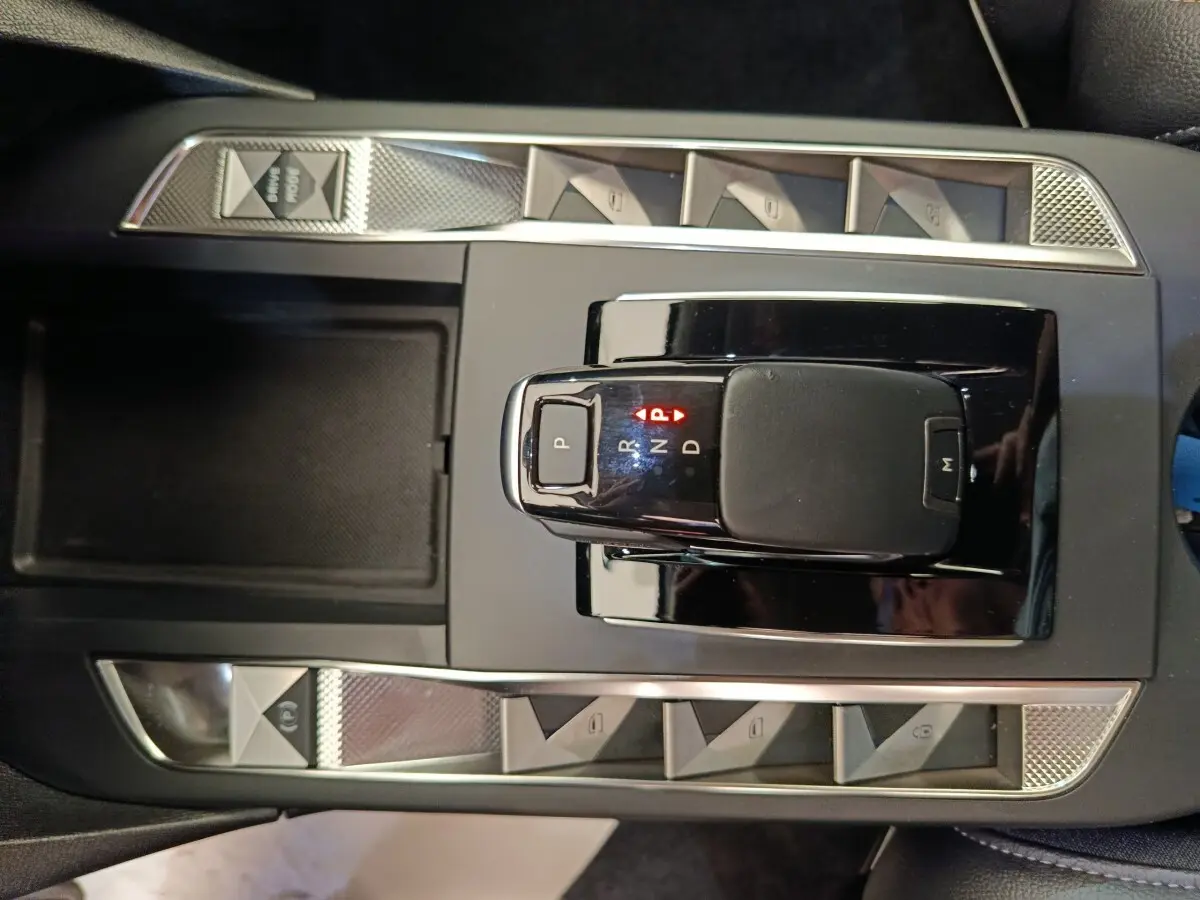 Vue plongeante sur la console centrale noire de la DS3 2024 avec levier de boîte auto et boutons argentés.