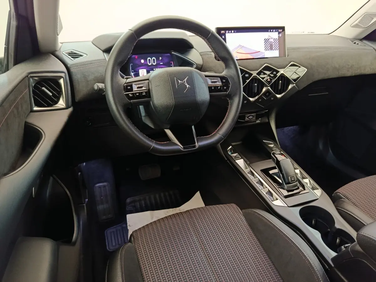 Vue intérieure côté conducteur du DS3 2024 gris foncé, volant cuir, écran tactile et console centrale design géométrique.