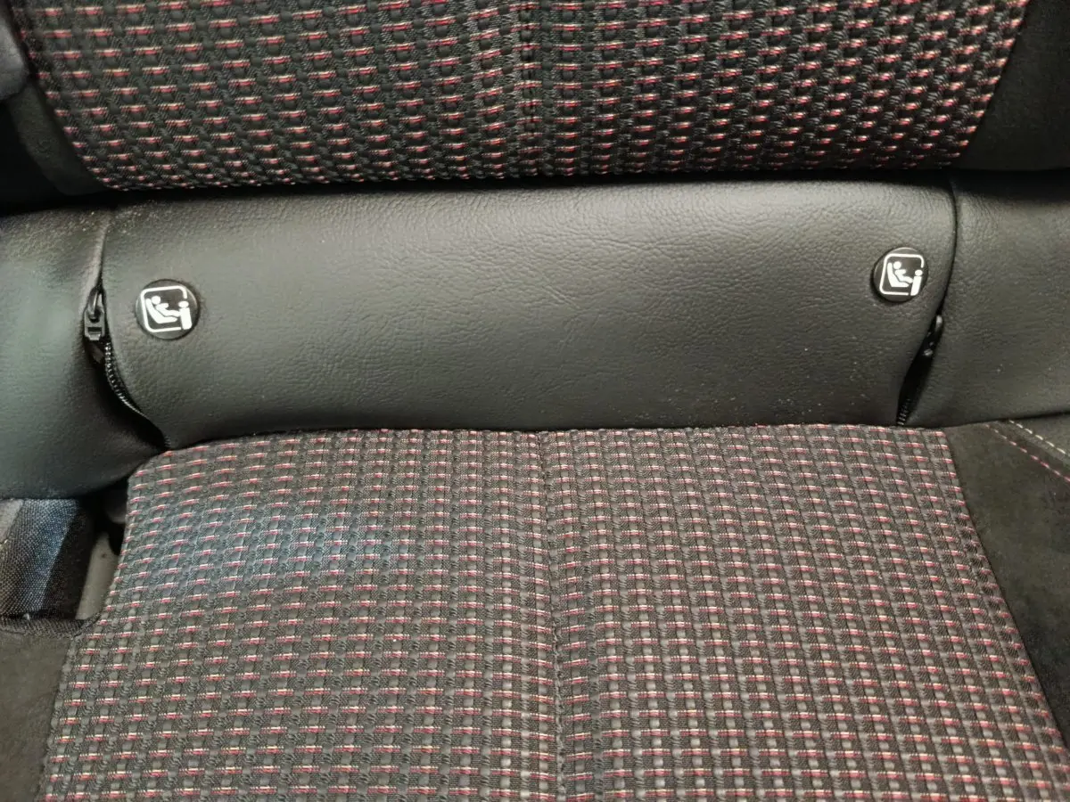 Gros plan sur la banquette arrière du DS3 2024, tissu noir à motifs rouges avec fixations Isofix visibles.