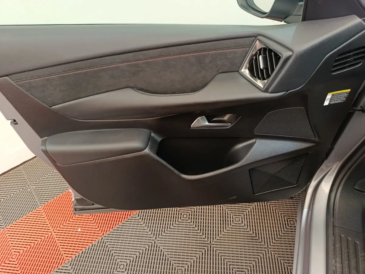 Vue intérieure côté gauche de la porte avant gris foncé du DS3 2024 avec garniture noire et surpiqûres rouges.