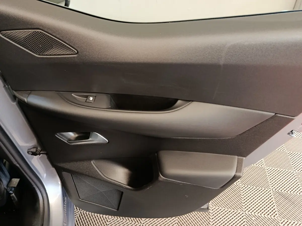Vue rapprochée de la porte arrière gauche gris foncé du DS3 2024 avec poignée intérieure et commande de vitre.