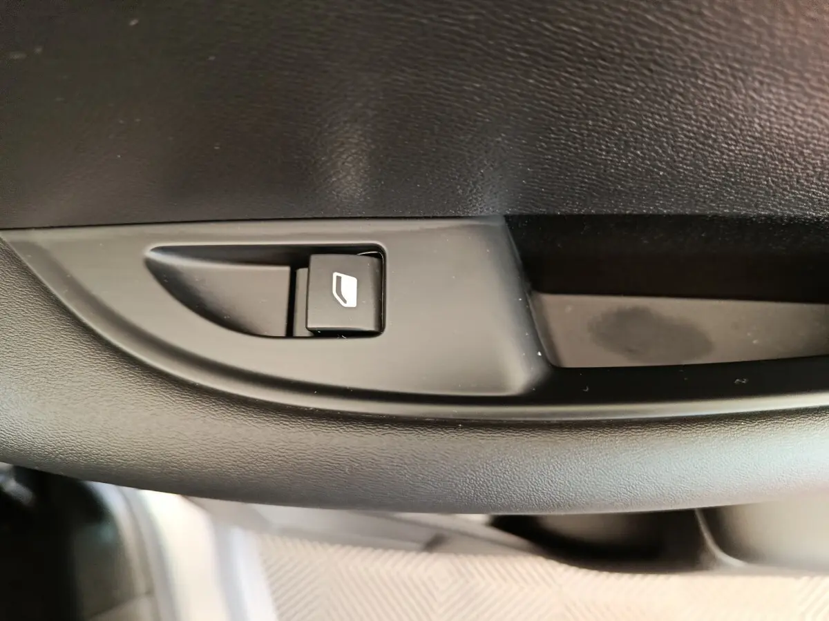 Détail du bouton de commande de lève-vitre sur la porte intérieure noire d'une DS3 2024 gris foncé.