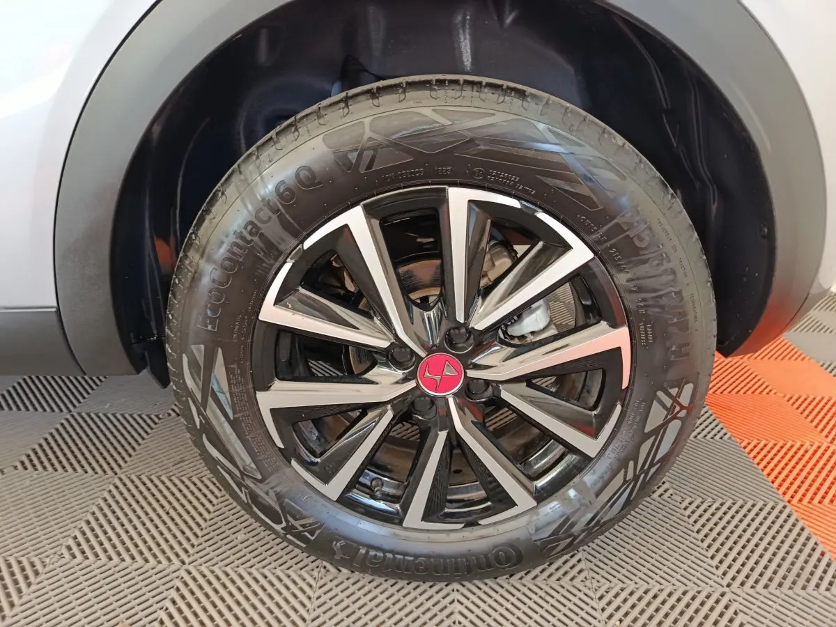 Gros plan sur la roue avant droite avec jante alliage noir et argent et logo DS rouge sur un DS3 gris foncé.