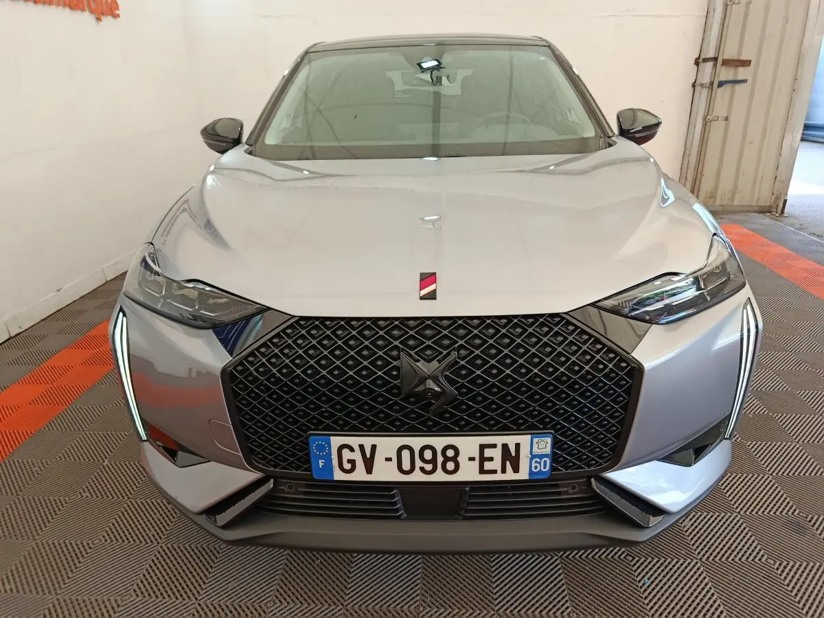 Vue frontale d'une DS3 2024 gris foncé avec calandre noire à motif losange et feux LED verticaux distinctifs.