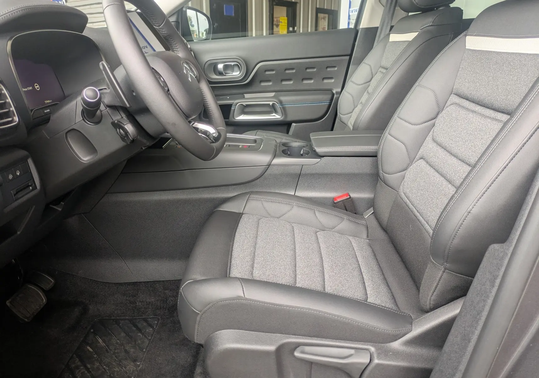 Vue intérieure côté conducteur du Citroën C5 Aircross 2025, sièges tissu et cuir gris avec volant multifonction croûte de cuir.