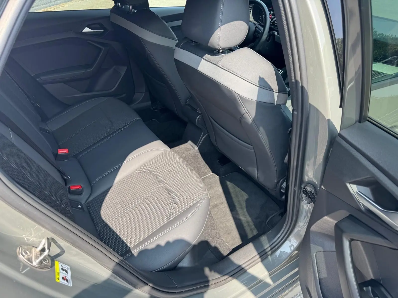 Vue intérieure côté arrière droit d'une Audi A1 Sportback gris avec sièges arrière en cuir et tissu gris.