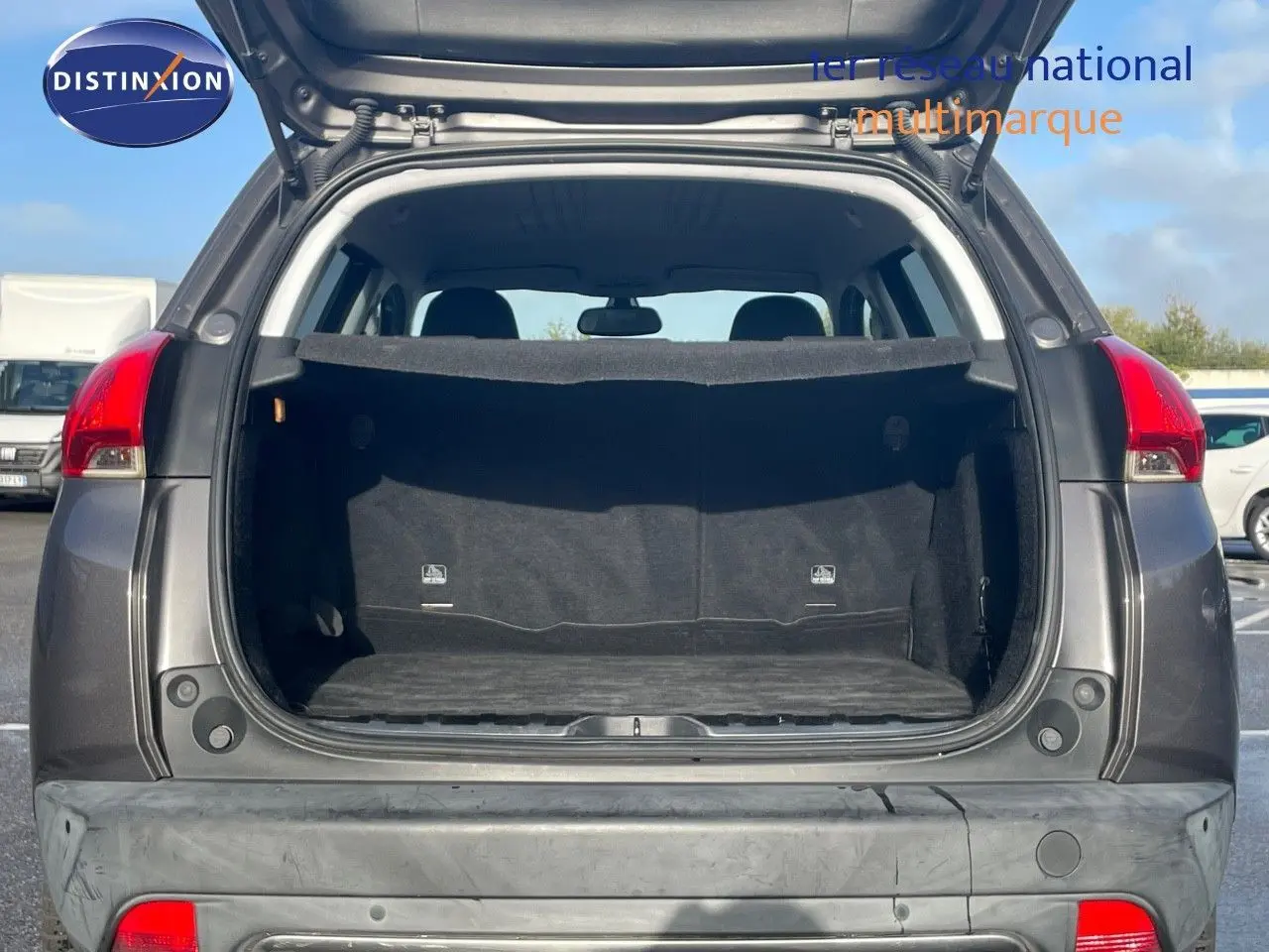 Vue arrière ouverte du coffre d'un Peugeot 2008 gris platinium métal, montrant l'espace de chargement vide.