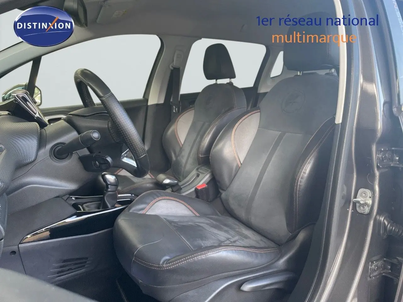 Vue intérieure côté conducteur du Peugeot 2008 gris platinium, mettant en valeur les sièges en cuir noir avec surpiqûres marron.