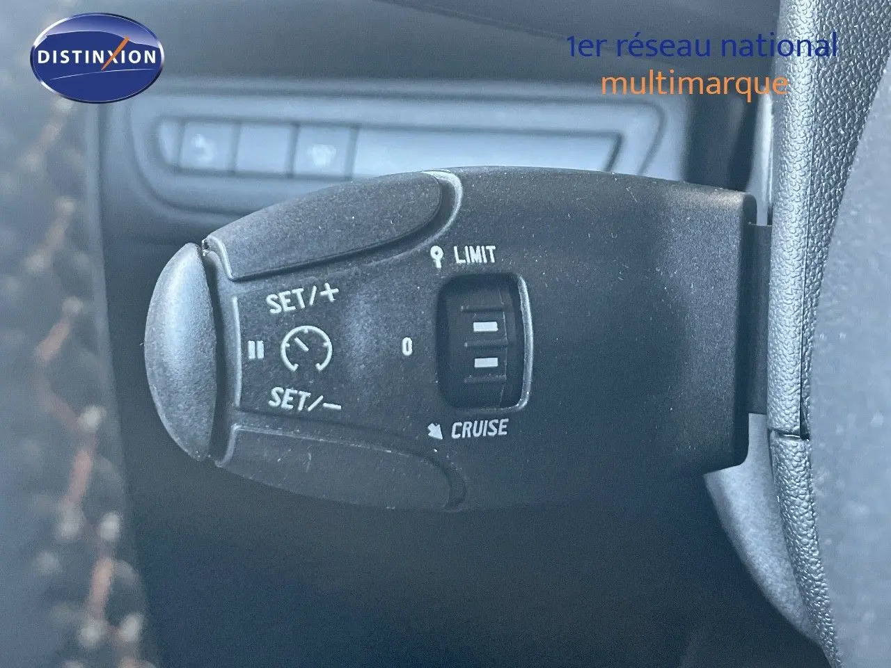 Gros plan sur la commande de régulateur de vitesse à gauche du volant dans un Peugeot 2008 gris platinium de 2019.