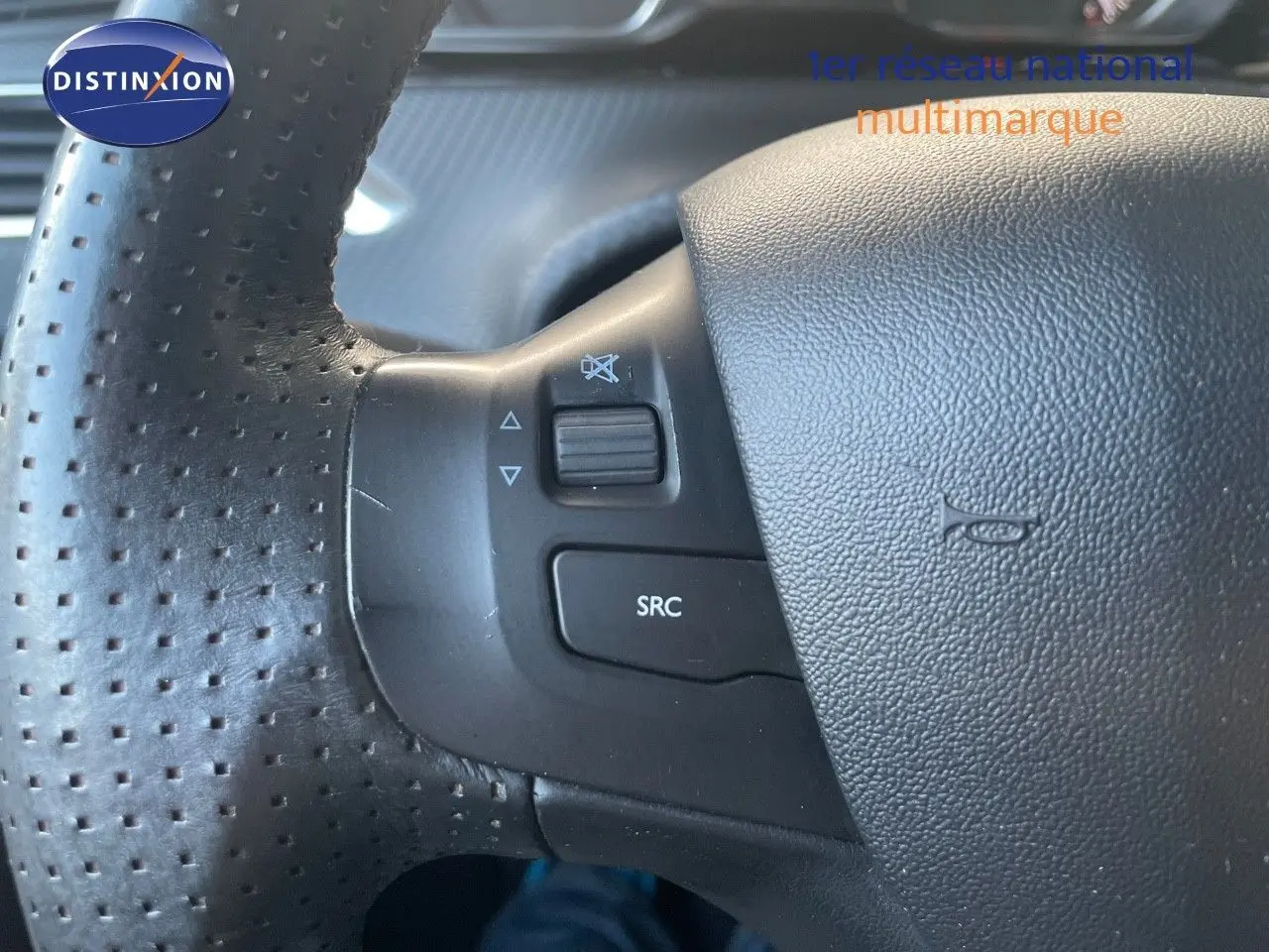 Gros plan sur les commandes gauche du volant en cuir perforé noir du Peugeot 2008 gris platinium 2019.