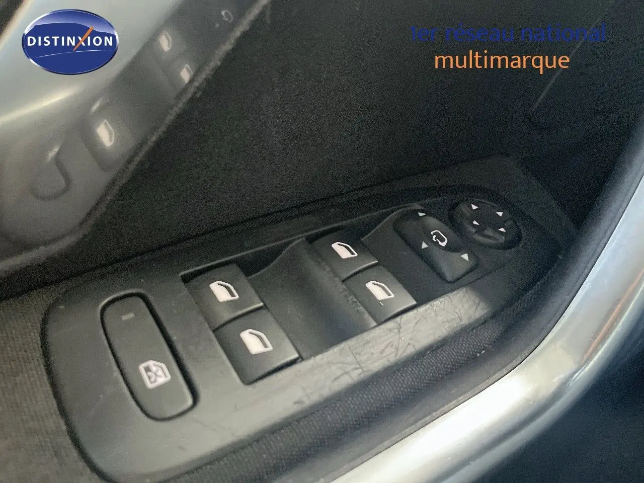 Gros plan sur les commandes des vitres électriques côté gauche d’une Peugeot 2008 gris platinium de 2019.