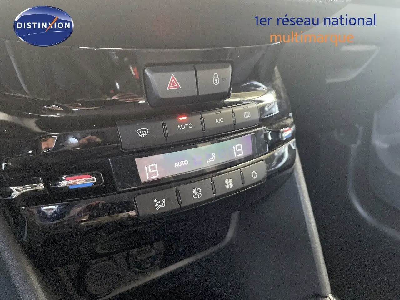 Gros plan sur la console centrale noire brillante du Peugeot 2008, affichant la climatisation automatique à 19°C.
