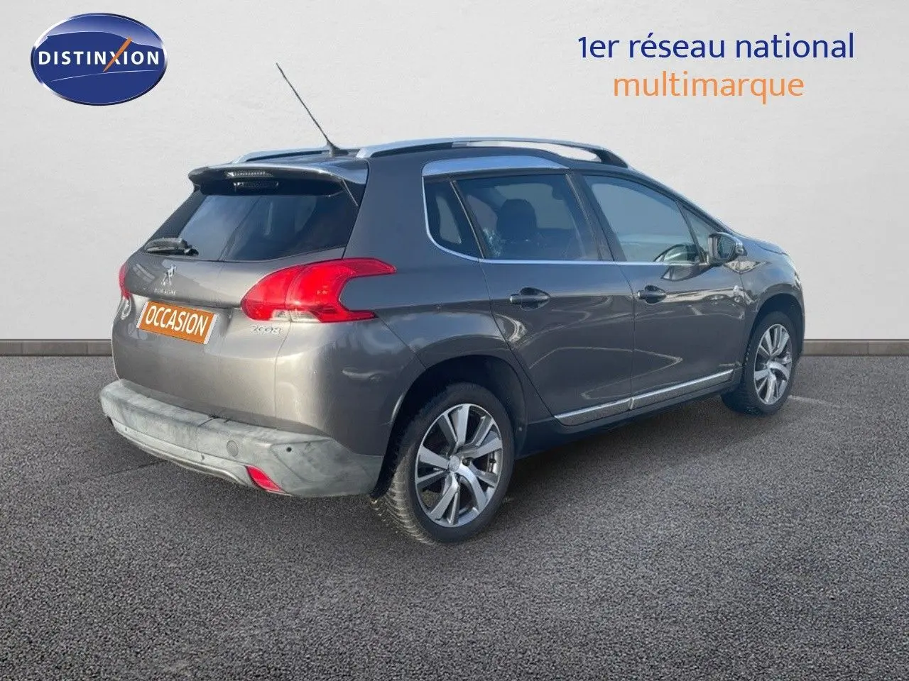 Peugeot 2008 gris platinium métal en 3/4 arrière droit, avec jantes alliage et barres de toit visibles.