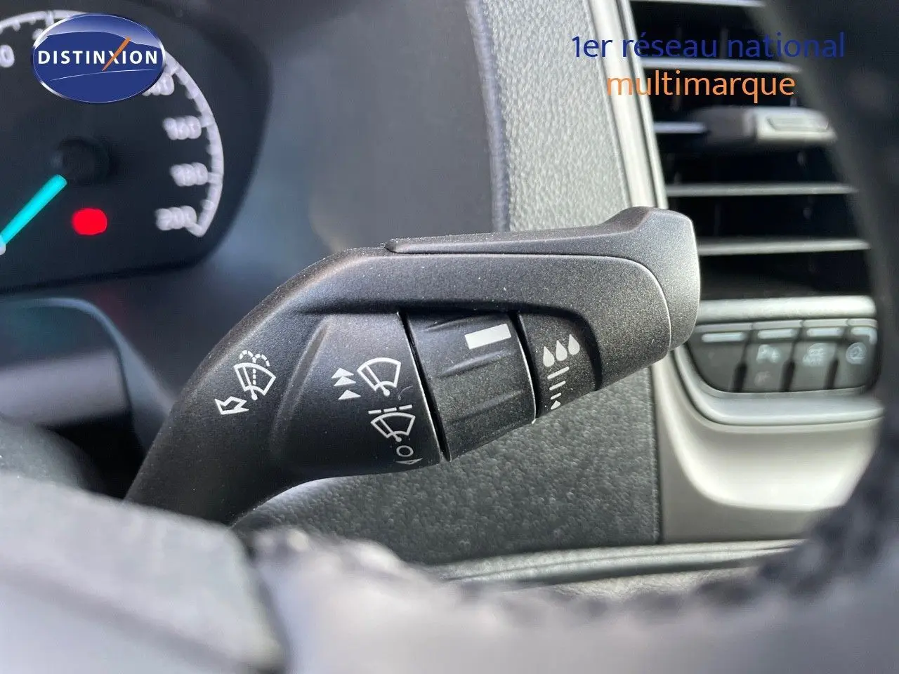 Gros plan sur la commande d’essuie-glace à gauche du volant dans l’habitacle d’un Ford Transit Fourgon blanc 2023.