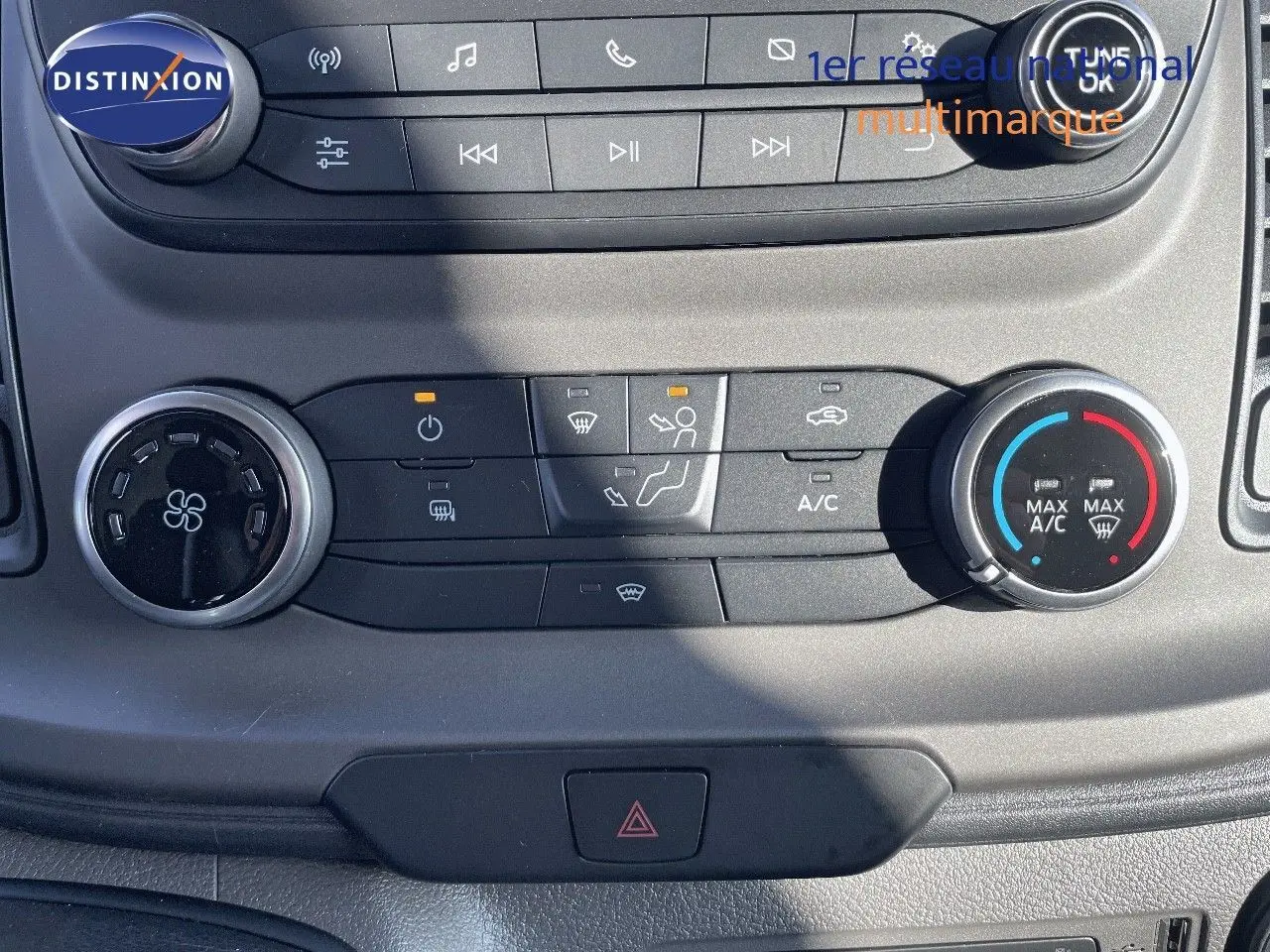 Vue rapprochée du tableau de bord du Ford Transit Fourgon blanc, montrant les commandes de climatisation et audio.