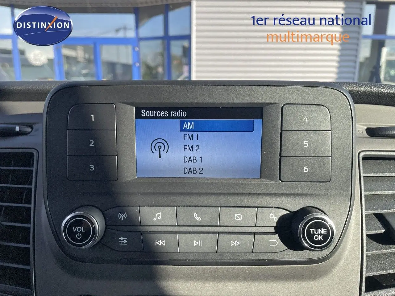 Gros plan sur l'écran radio et les commandes du tableau de bord du Ford Transit Fourgon blanc 2023.