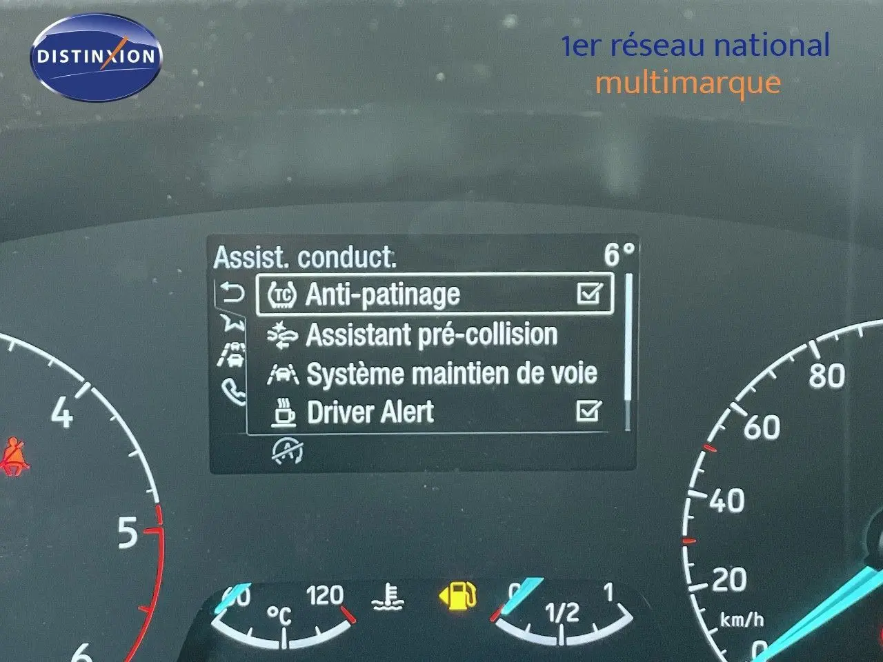Vue rapprochée du tableau de bord du Ford Transit Fourgon blanc 2023, affichant les aides à la conduite activées.