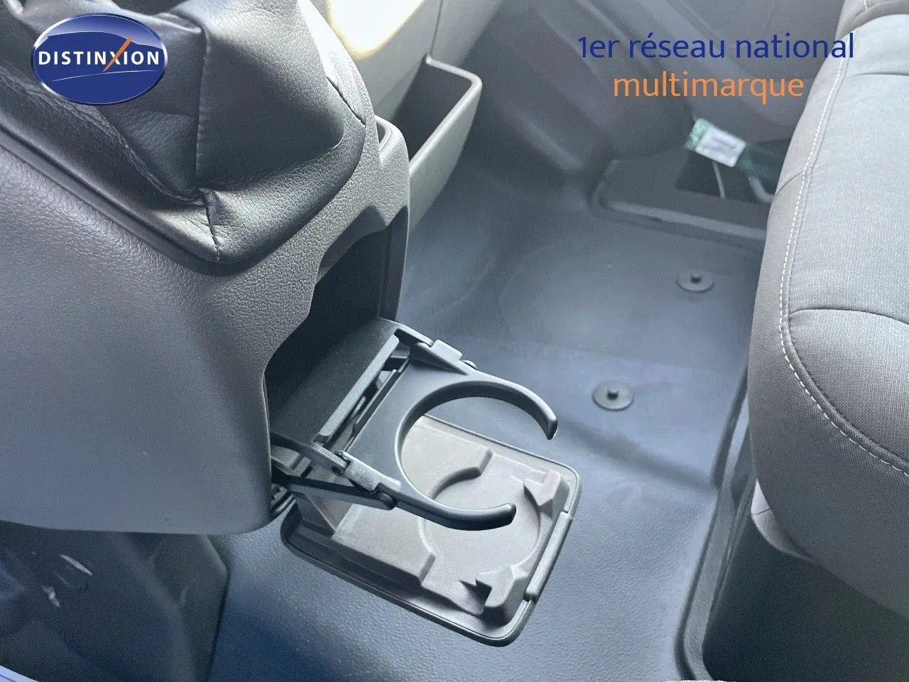 Détail de porte-gobelet déployé entre les sièges avant du Ford Transit Fourgon blanc, intérieur gris.
