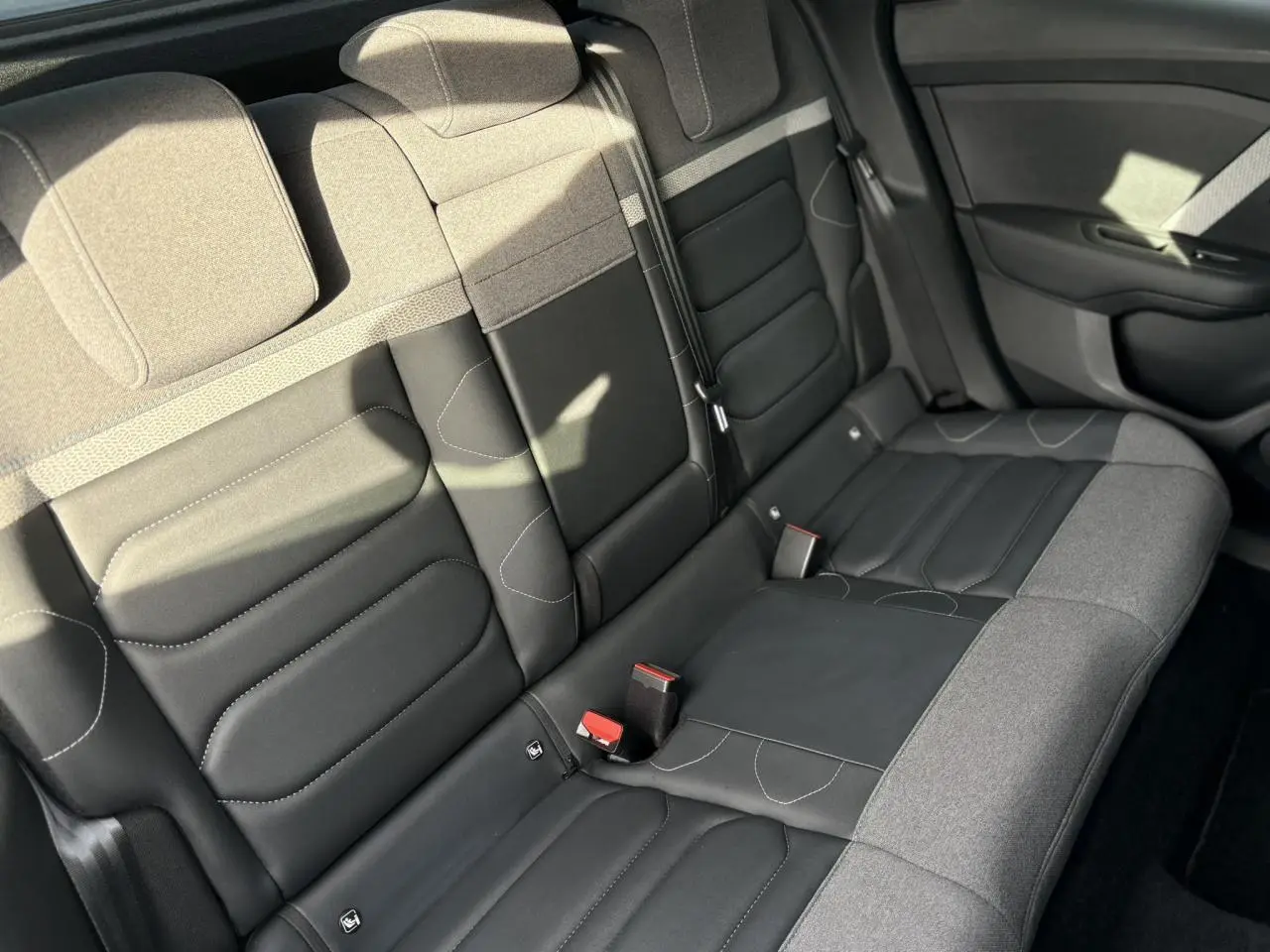Vue intérieure du siège arrière droit de la Citroën C4 2024 avec sellerie bicolore gris et noir, détails couture visibles.