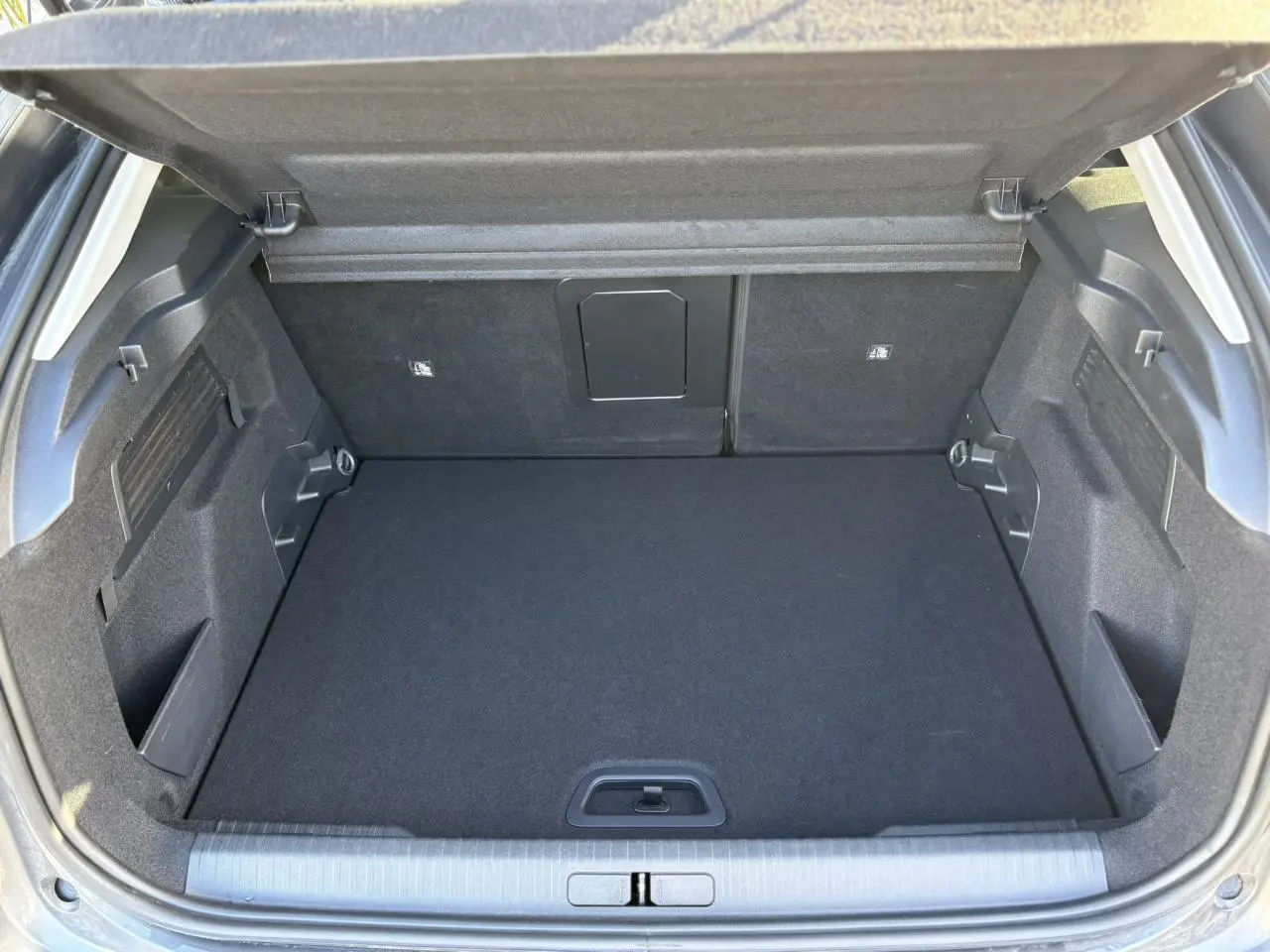 Coffre ouvert vu de l'arrière d'une Citroën C4 2024 gris Platinium, espace de chargement propre et modulable.